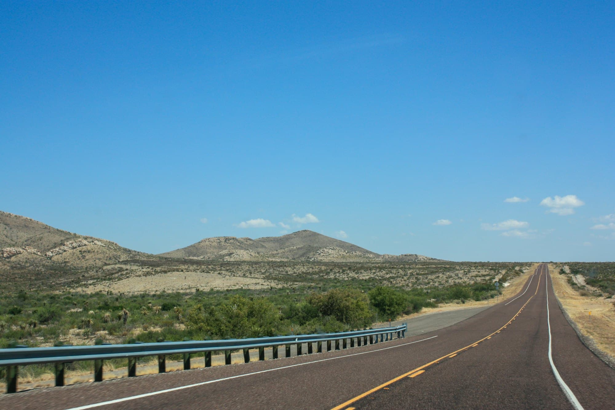 Carretera de dos carriles entre montañas vista desde un punto elevado